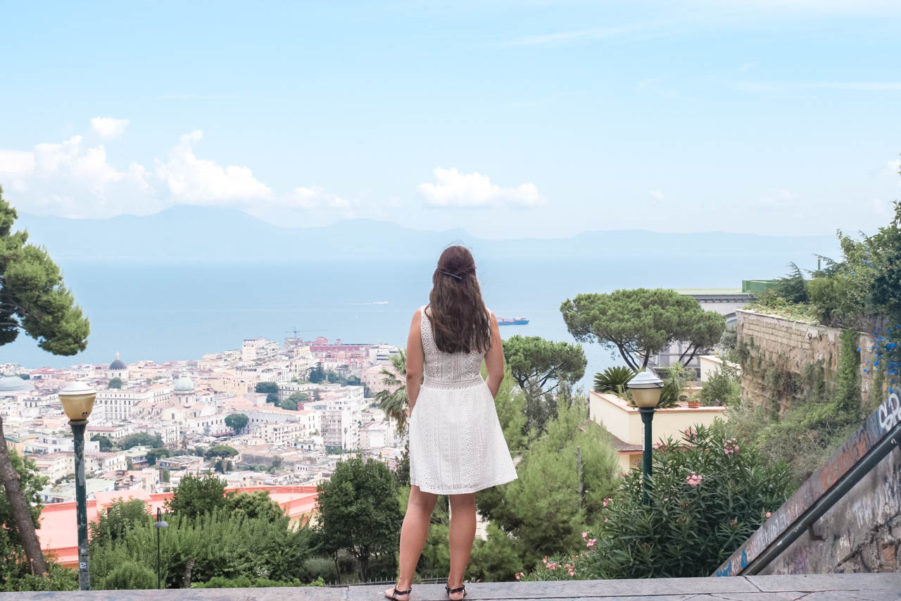 A girl in a white lace dress looking out over the Bay of Naples