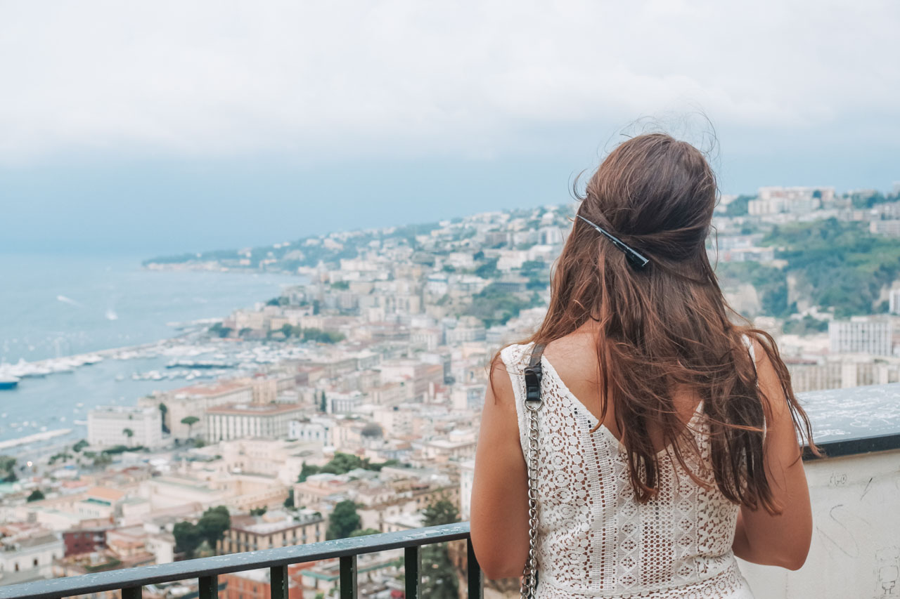 A girl in a white dress standing on a terrace overlooking the Bay of Naples