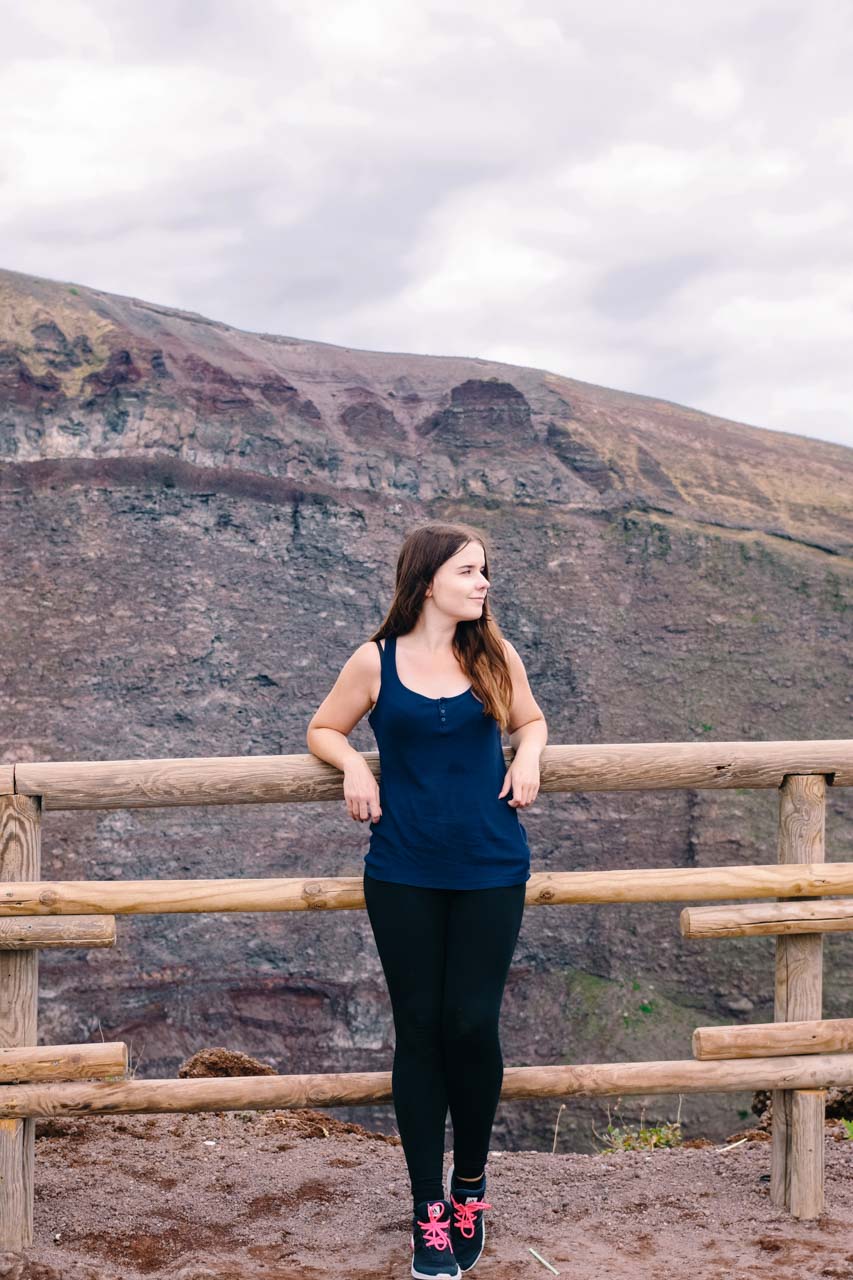 A girl leaning against the wooden fence around the crater of Mount Vesuvius