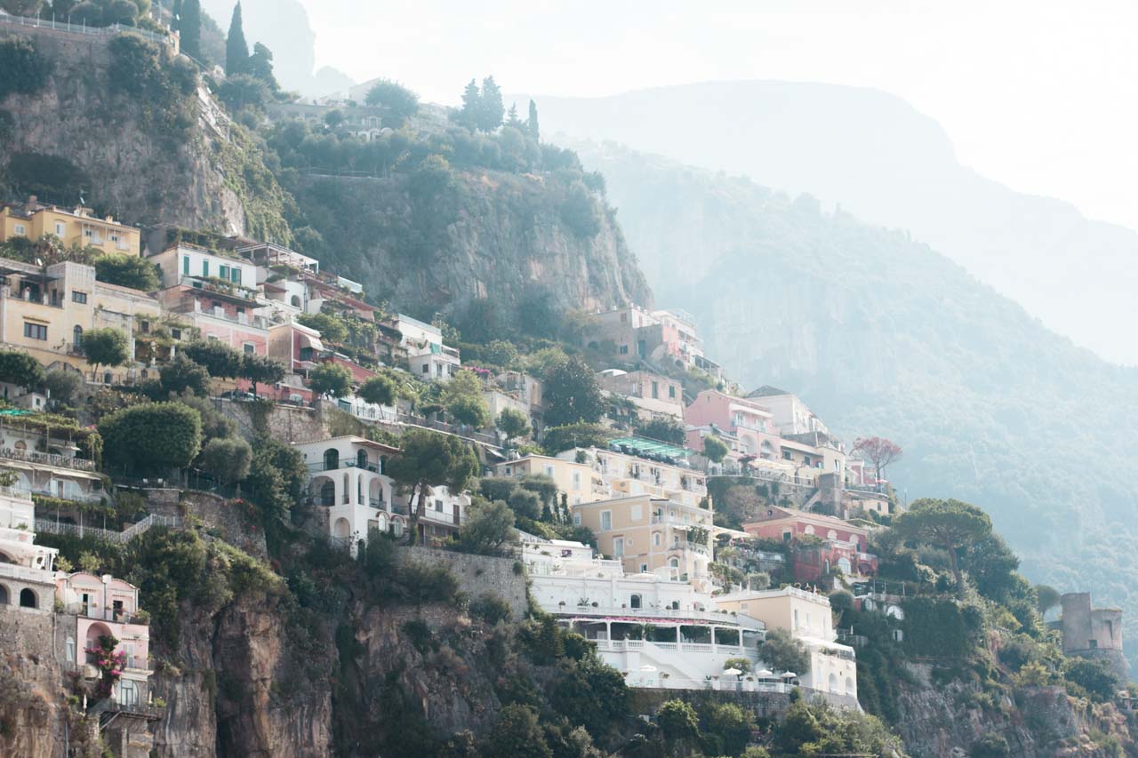 Hillside houses in Positano, Italy with fog-covered mountains in the background