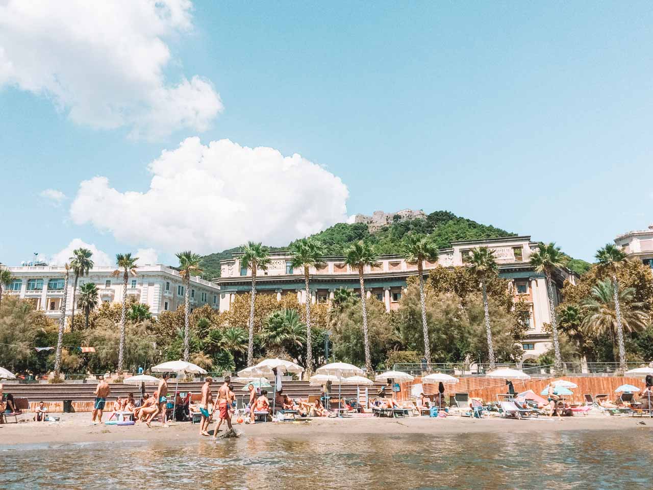 Tourists on the beach in Salerno and Castello di Arechi seen from the water