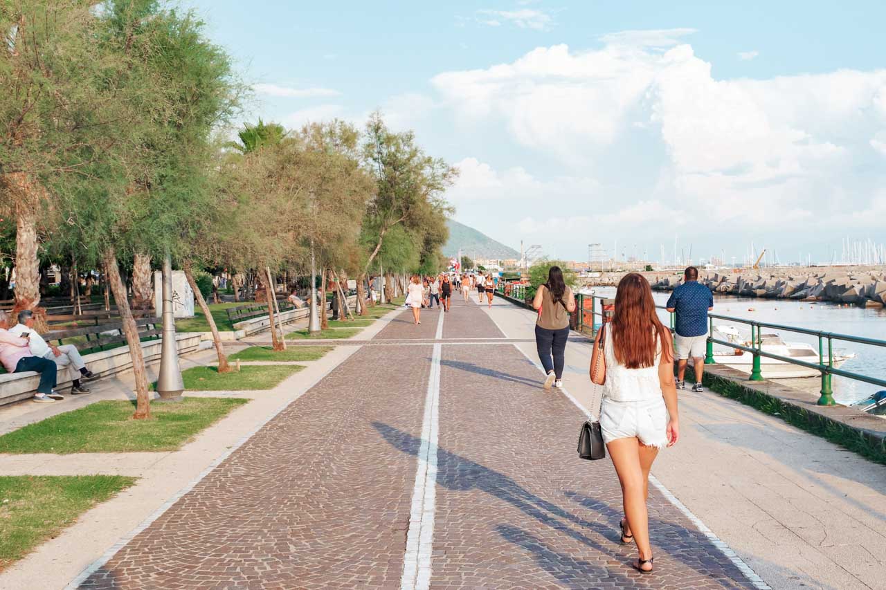 A girl walking alongside the Lungomare Trieste promenade in Salerno, Italy