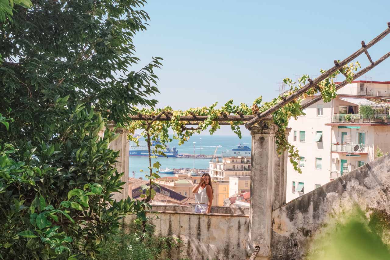 A girl standing inside Giardino della Minerva with vines hanging above her head