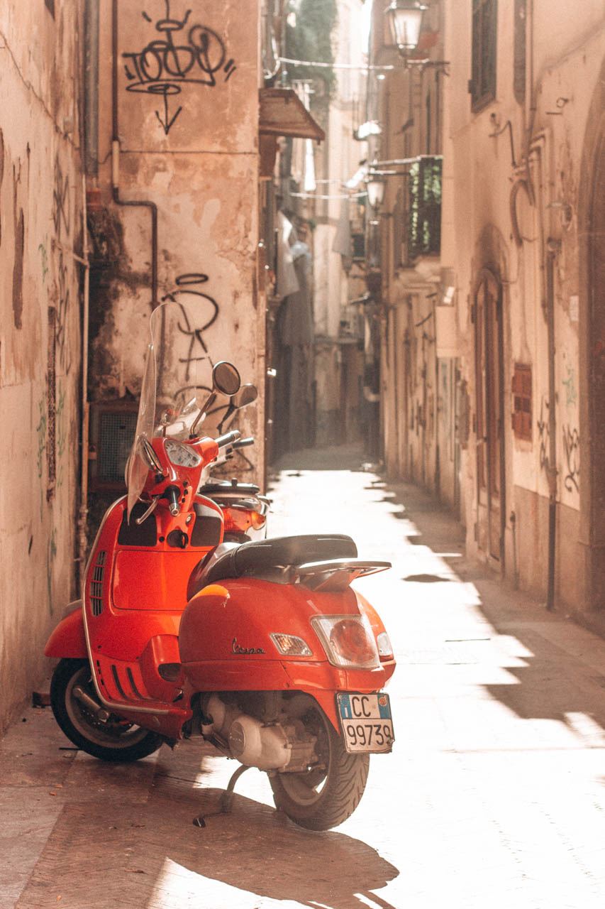 A red scooter parked in an alley in Salerno, Italy