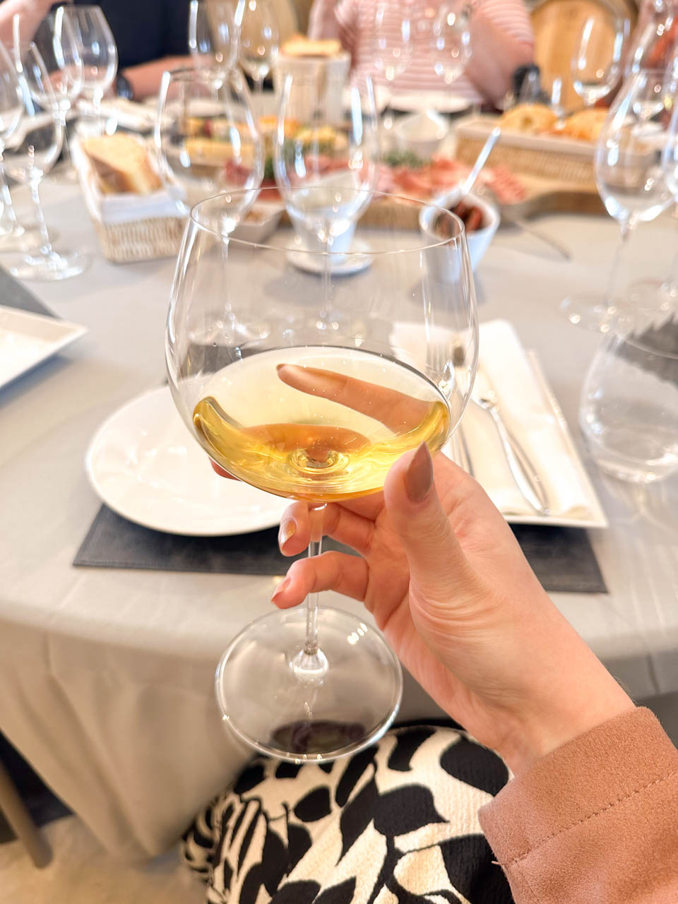 A woman's hand holding up a glass with white chardonnay wine