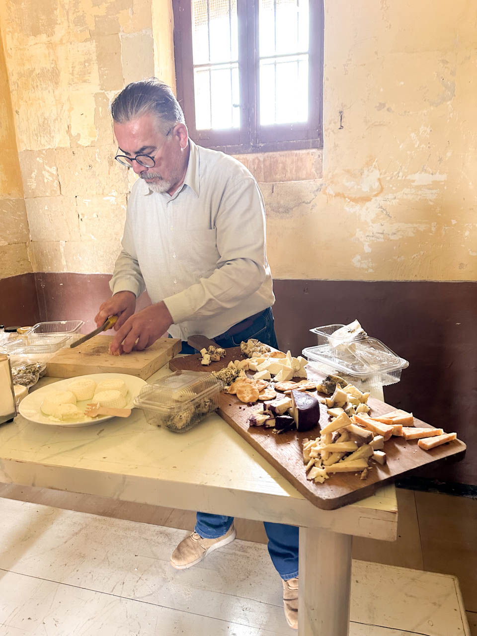 A chef cutting Maltese cheese to be placed on a wooden serving board