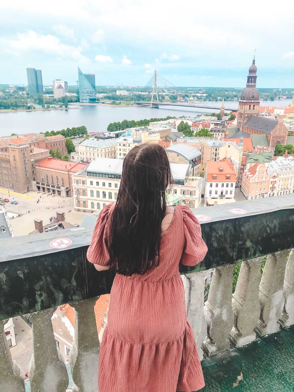 A girl in a pink dress admiring the view from the tower of St. Peter's Church