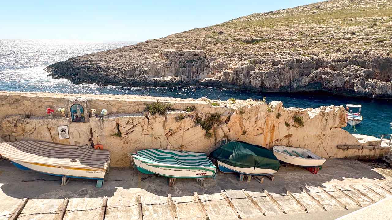 A row of small boats docked at the port where you can get a trip to the Blue Grotto in Malta
