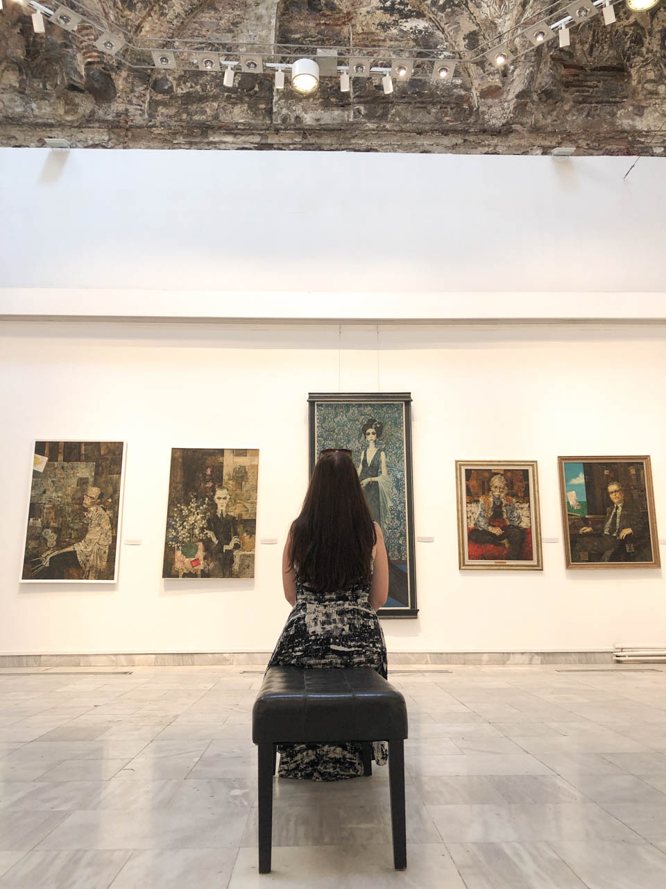 Brunette sitting down and admiring paintings at Daut Pasha Hamam in Skopje, North Macedonia