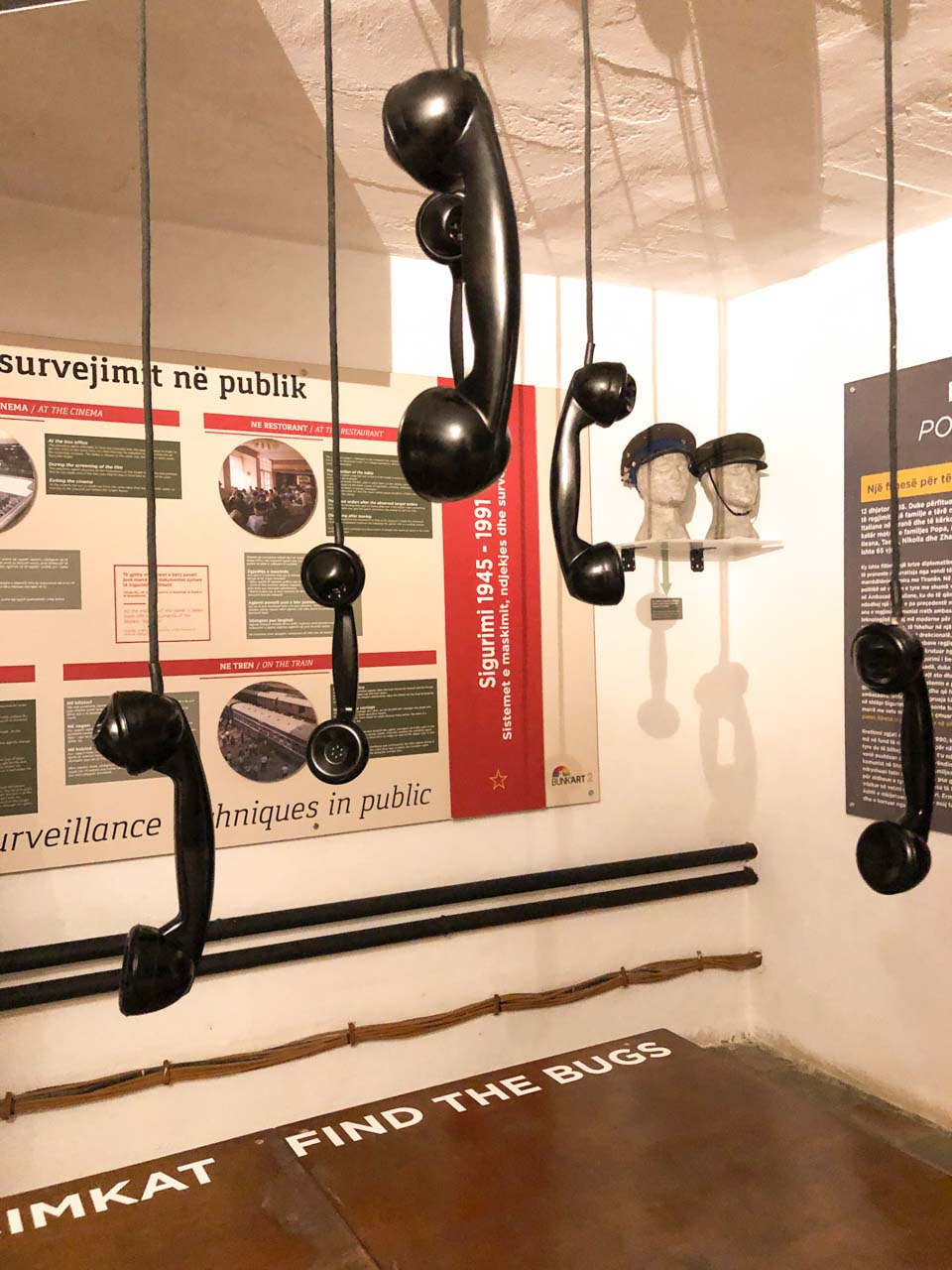 Old phone receivers hanging from the ceiling inside a room at Bunk'Art 2 dedicated to listening devices/bugs