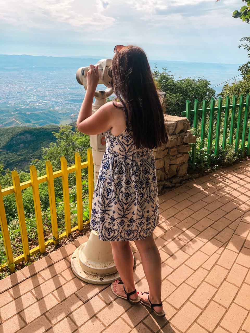 Woman looking through binoculars on top of Mount Dajti at the panorama of Tirana