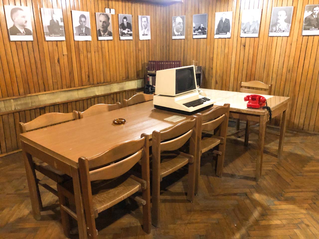 Room at Bunk'Art 2 with wooden panelling, an old computer on a table, and black and white portrait photos on the walls