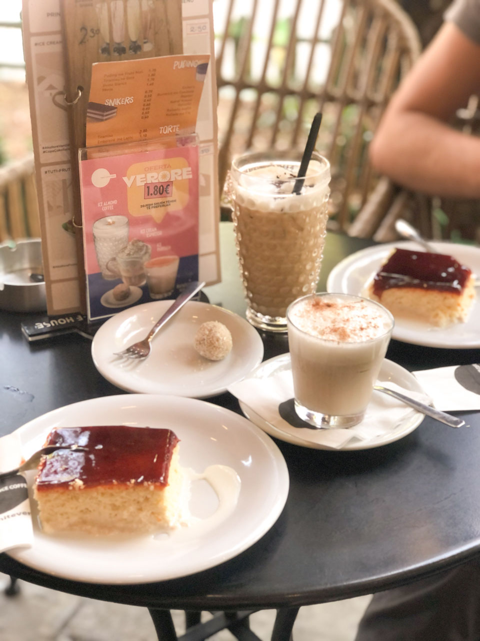 Two slices of trilece cake, two cups of coffee, and a Balkan-style raffaello on a table