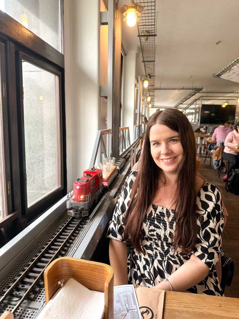 Miniature train going past a smiling brunette at Výtopna restaurant in Prague