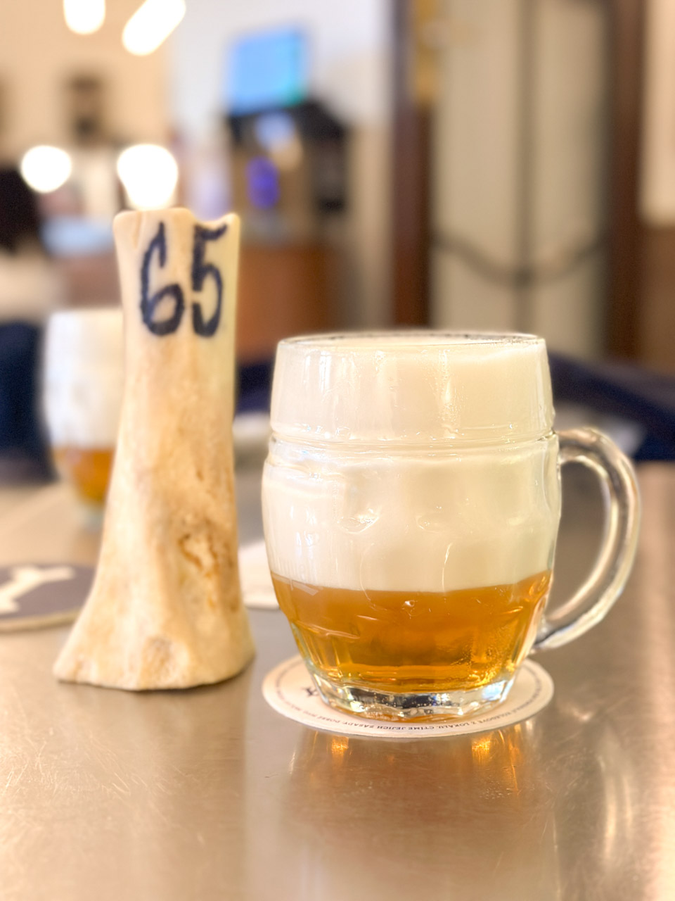 Glass of Mlíko on a table next to a bone with 65 written on it