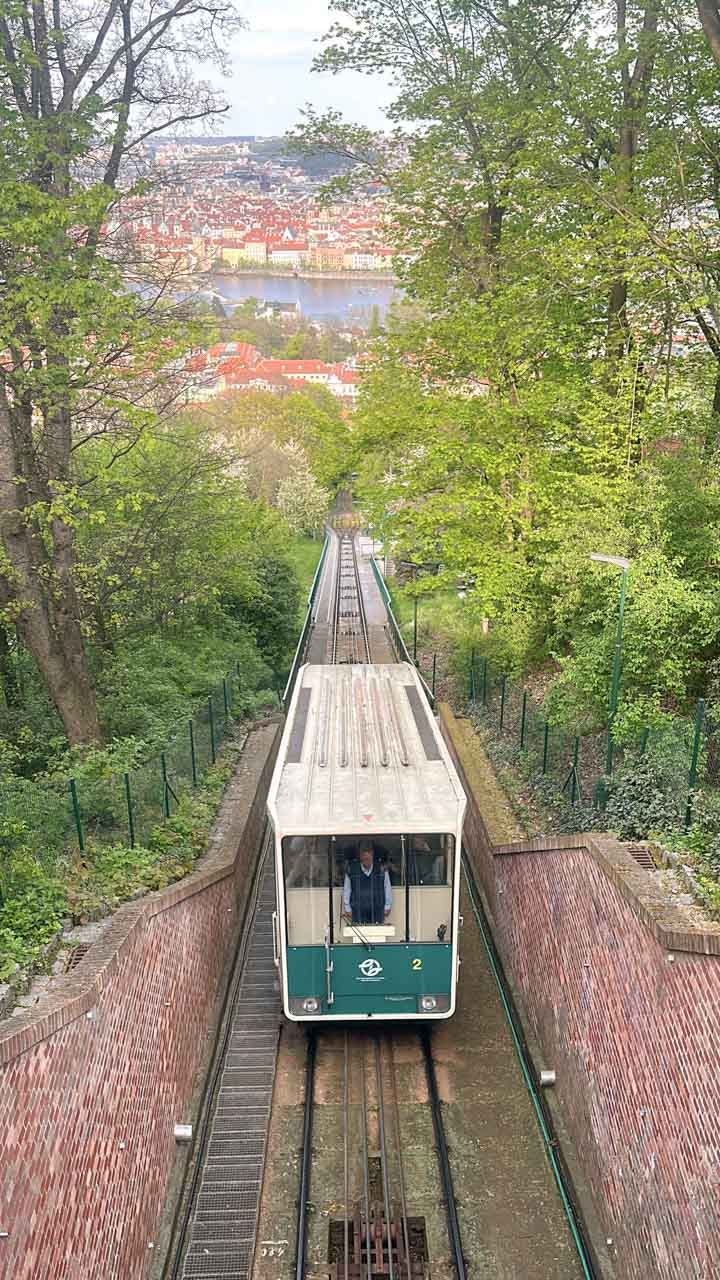 Funicular approaching the top of Petřín Hill with a panorama of Prague in the background