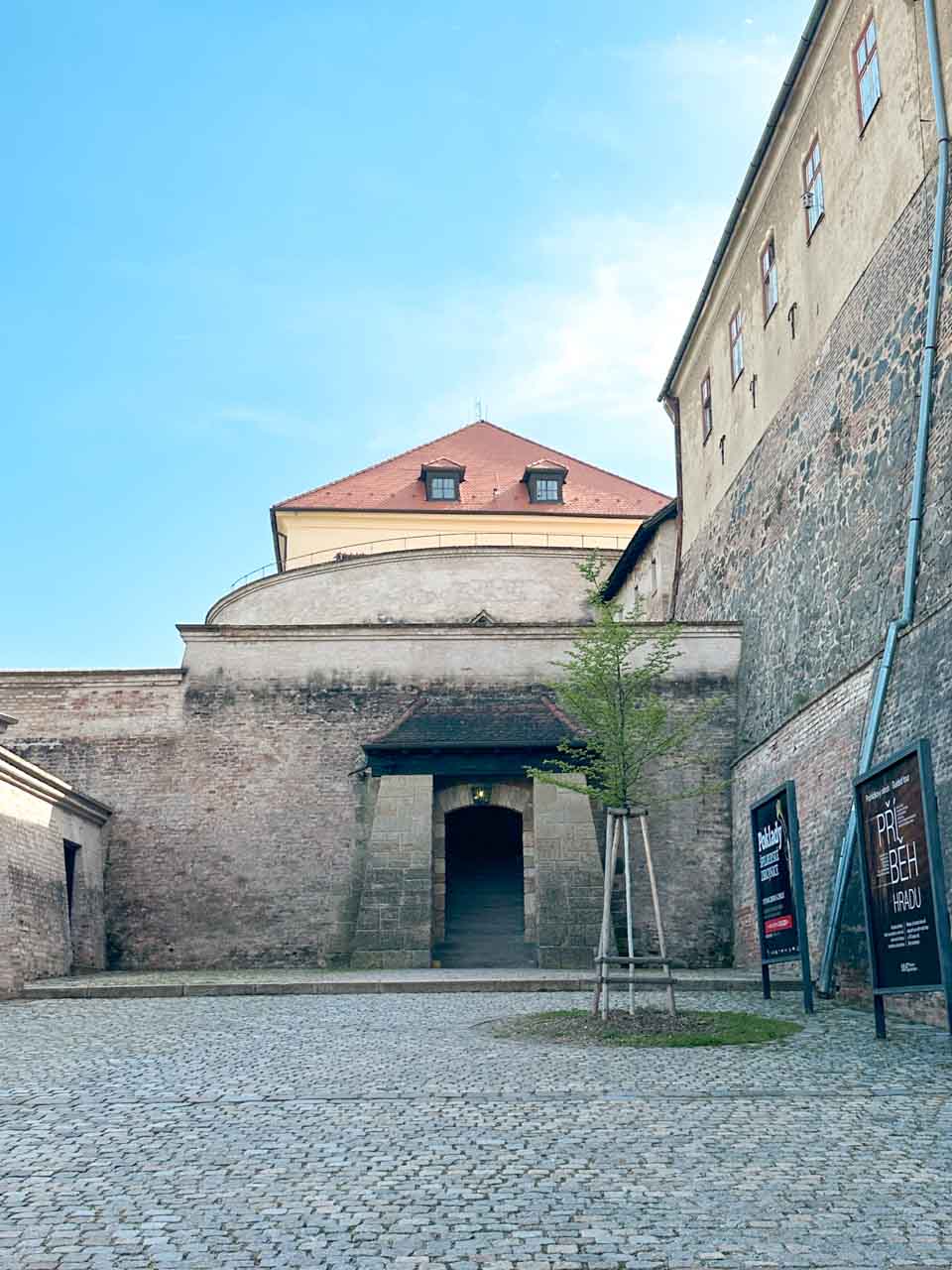 A historic courtyard inside the Špilberk Castle in Brno, Czech Republic with cobblestone and an archway entrance