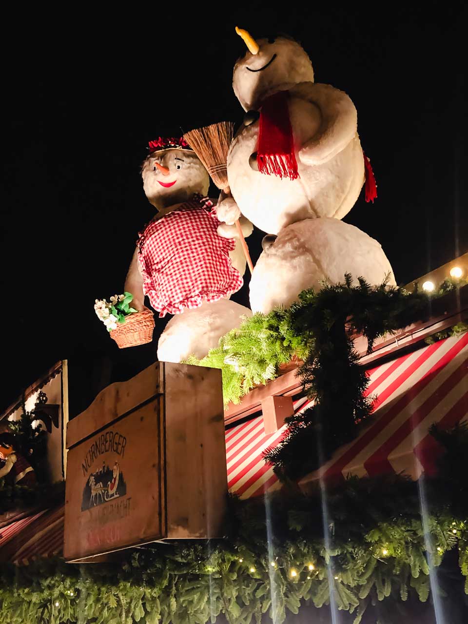Figures of a male and a female snowman perched atop a Christmas market stall in Nuremberg