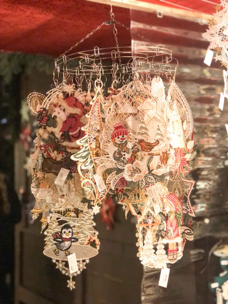Elegant lace Christmas decorations featuring angels and other festive motifs, delicately hanging at a Christkindlesmarkt stall