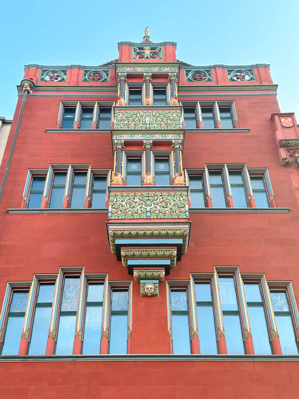 A detailed view of the vibrant green and red ornamental exterior of Basel Town Hall