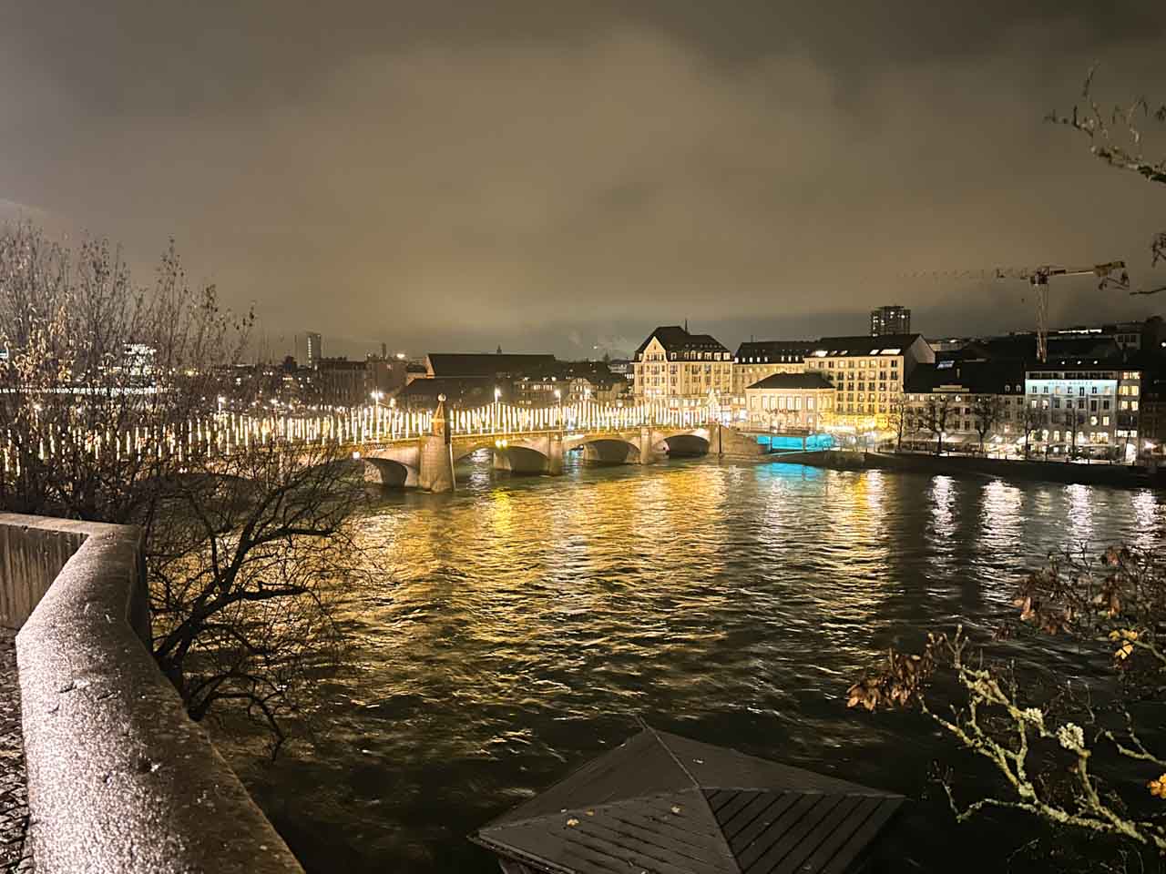 A nighttime view of The Middle Bridge in Basel, beautifully lit and reflected on the Rhine River