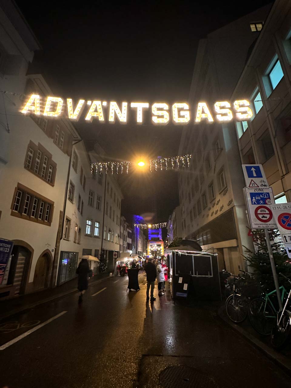 Rheingasse street in Basel during the Christmas season with 'ADVANTSGASS' lit up above and festive decorations