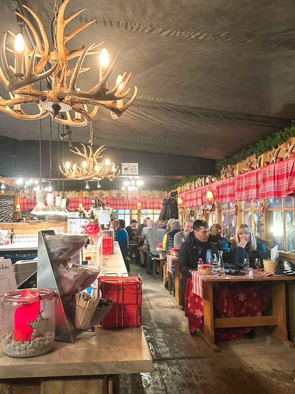 A cosy indoor seating area at the Wacker Fonduestübli restaurant in Basel with antler chandeliers and festive decorations