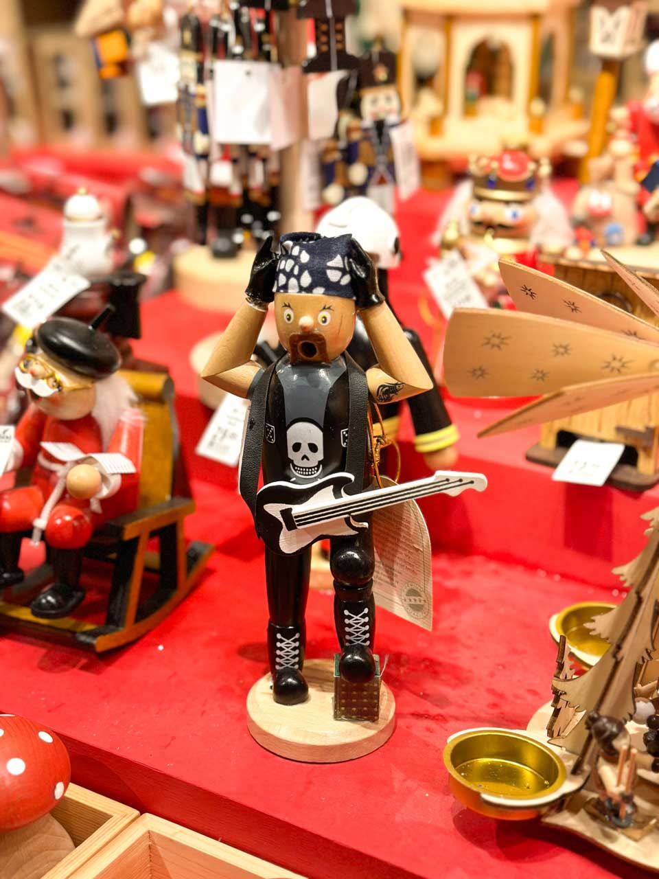 A quirky nutcracker figure styled as a rockstar with a pirate t-shirt, displayed at a Basel Christmas market stall