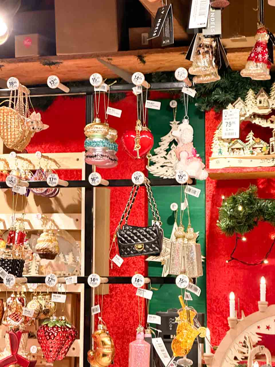 A diverse collection of Christmas ornaments, including macarons and handbags, with price tags, at a Basel Christmas market stall