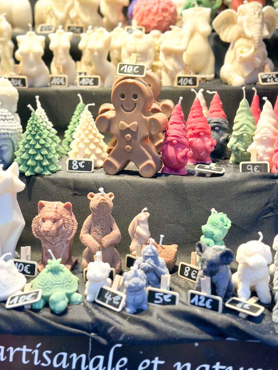 An assortment of handcrafted candles moulded into festive shapes and characters at a Christmas market in Colmar