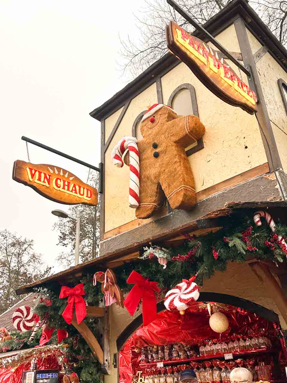 A large gingerbread man decoration hanging on the wall of a 'Vin Chaud' (hot wine) stall at a Christmas market in Colmar