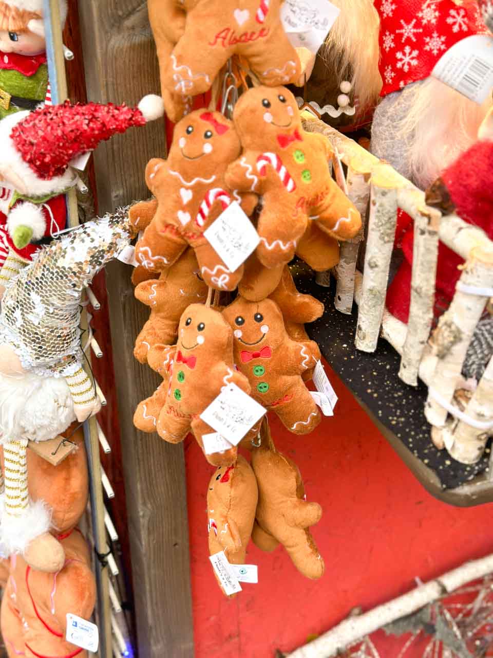 Plush gingerbread men ornaments with cheerful faces hanging at a Christmas market stall in Colmar
