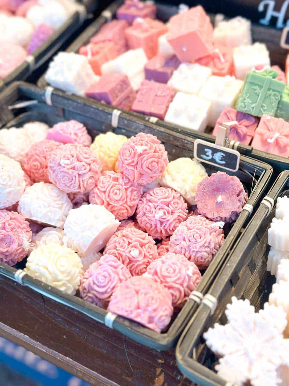 Handcrafted soaps shaped like roses and displayed in various colours at a Colmar Christmas market stall