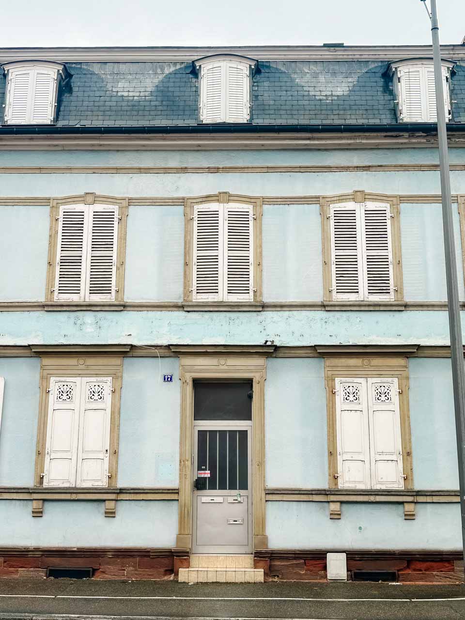 A light blue house with white shutters and a dark blue roof in Colmar, France