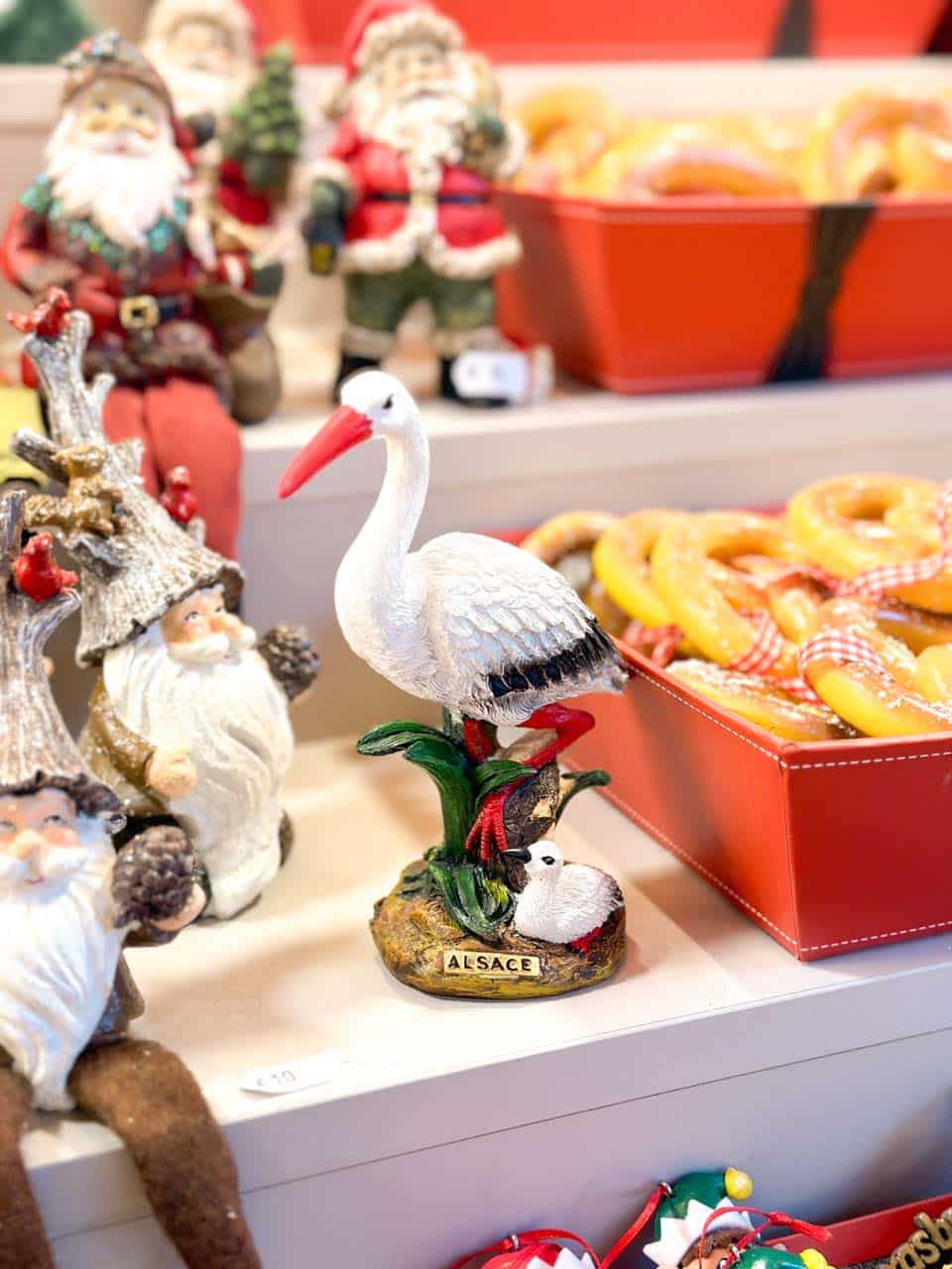 A white stork decoration nestled among seasonal figures and bright pretzels on display at a Strasbourg Christmas market