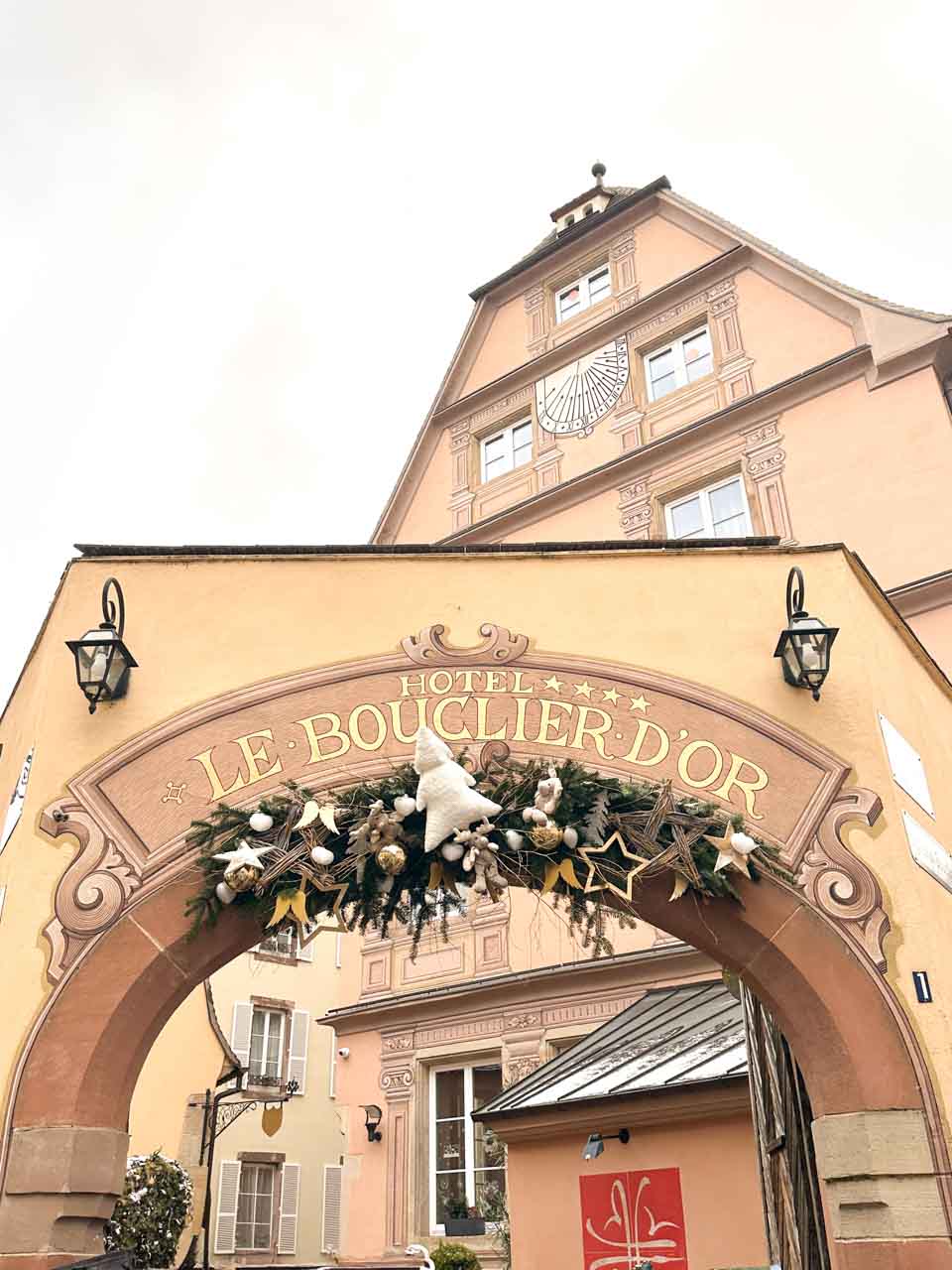 An elegant archway entrance to Hotel Le Bouclier d'Or in Strasbourg, festively decorated with greenery