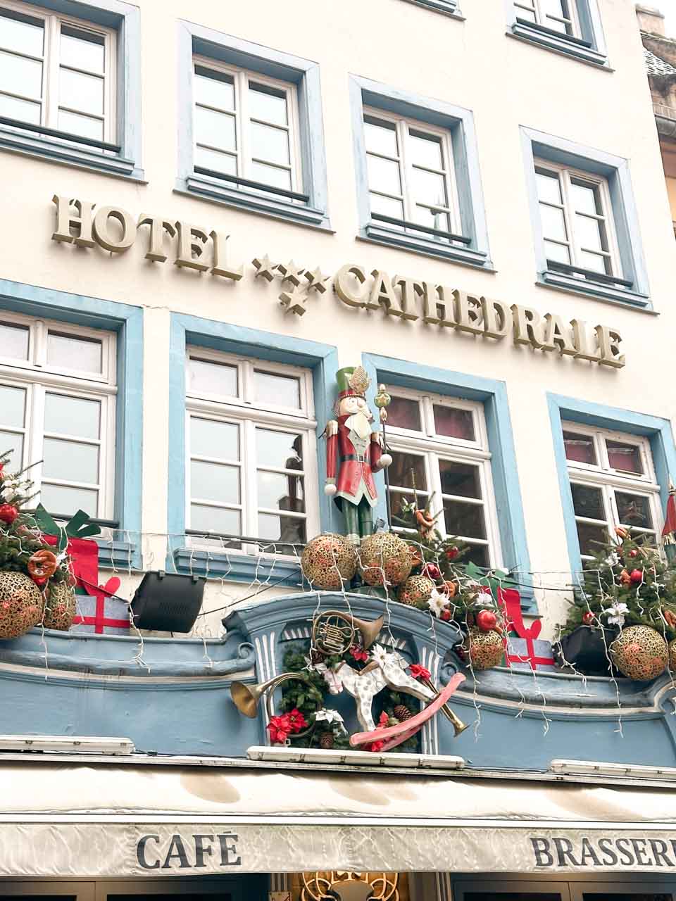 The façade of Hôtel Cathédrale in Strasbourg festively decorated with a nutcracker figure, baubles, and wreaths