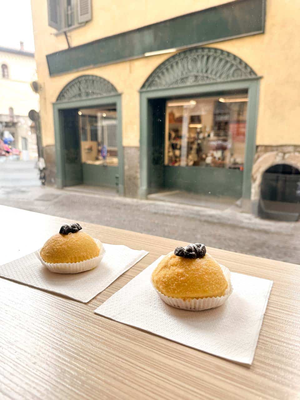 Two Polenta e Osei pastries placed on napkins on a café table in Bergamo, Italy