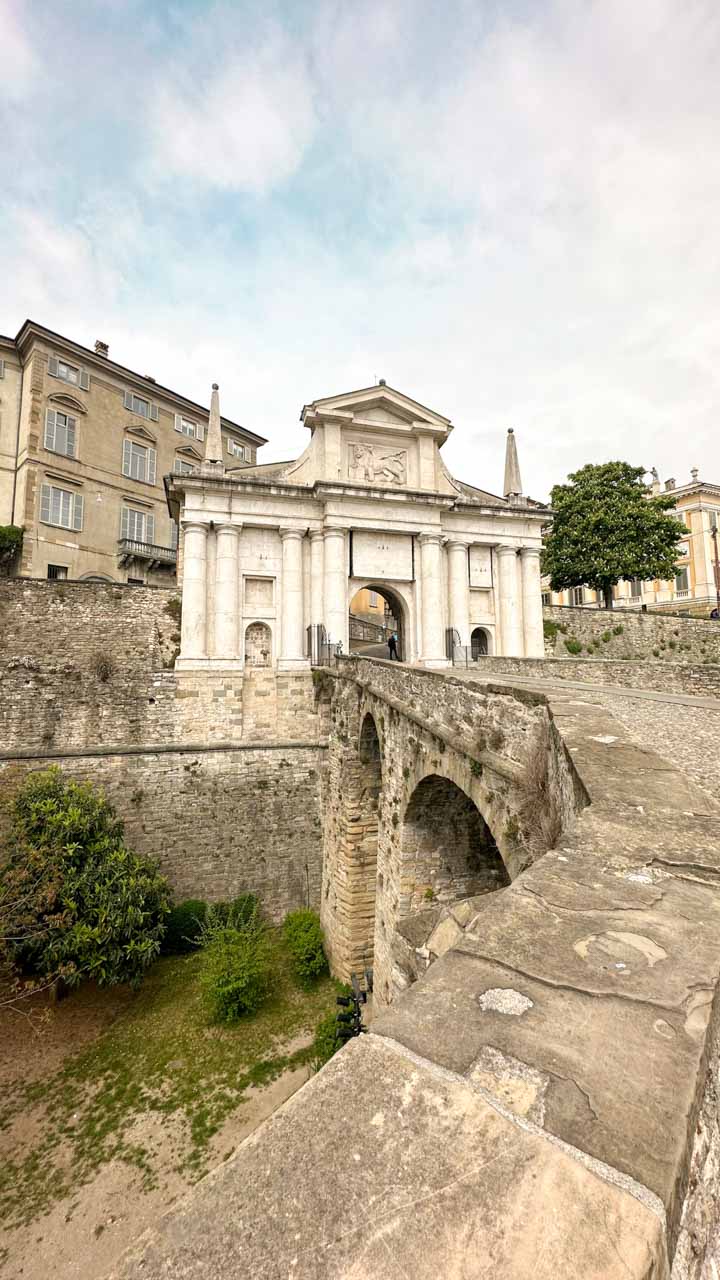 The historic Porta San Giacomo, a grand stone gateway with an arched entrance, leading into the old city of Bergamo