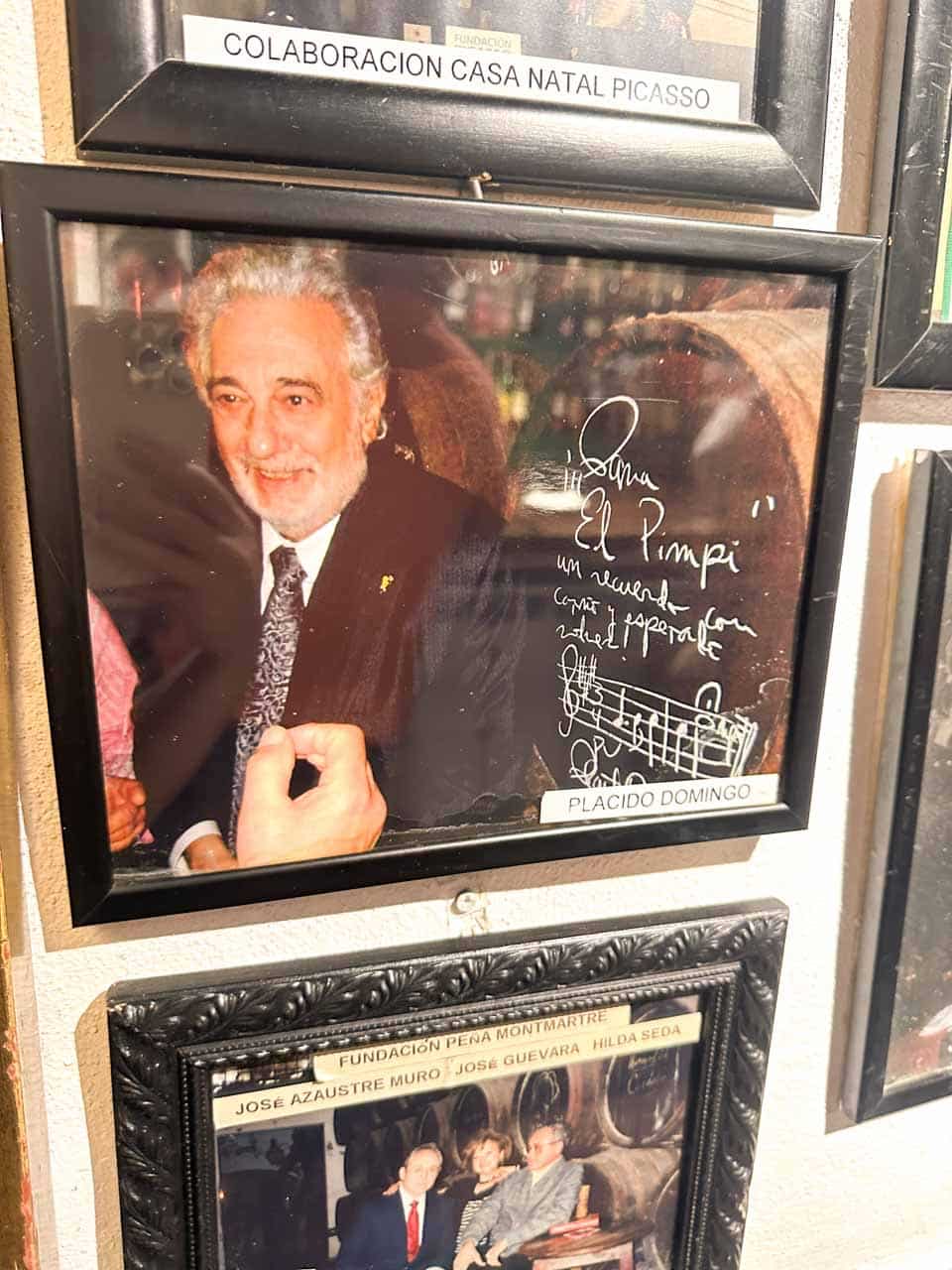 A signed photo of Placido Domingo on the wall of Bodega El Pimpi in Malaga, Spain, surrounded by other framed pictures