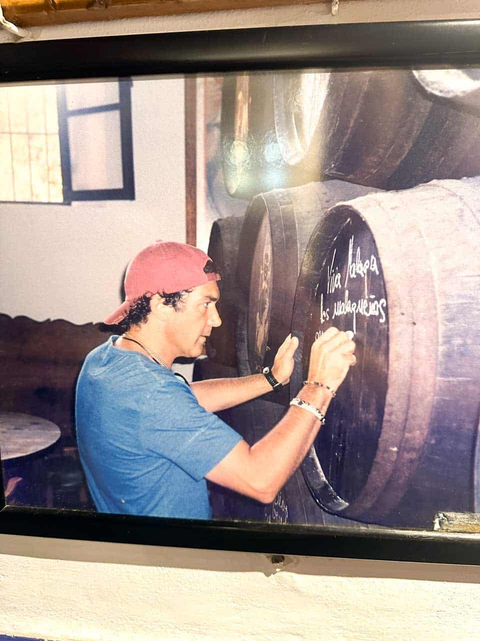 A photo capturing a moment of Antonio Banderas signing a wine barrel at Bodega El Pimpi in Malaga, Spain
