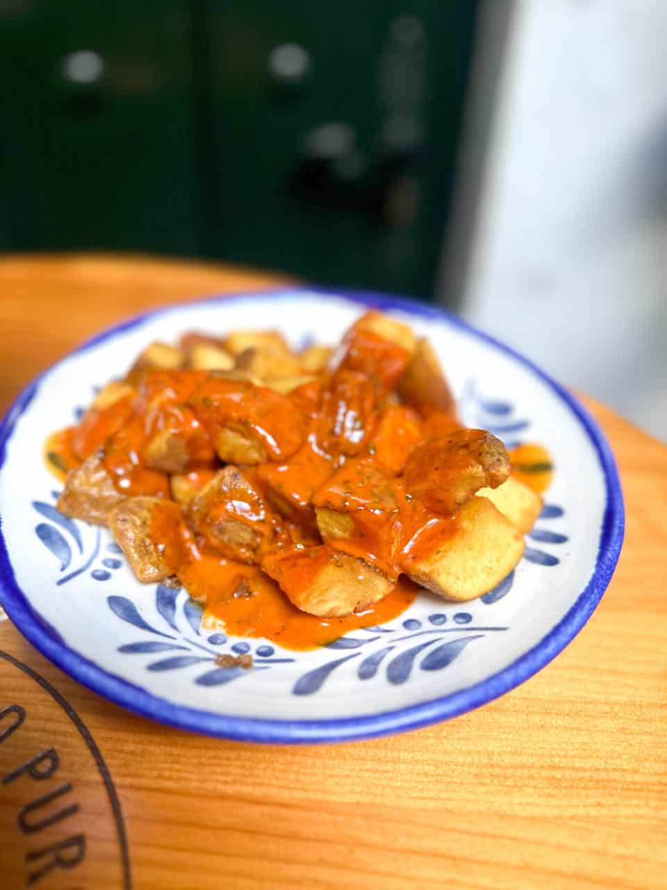 A close-up of patatas bravas served on a traditional Spanish ceramic plate