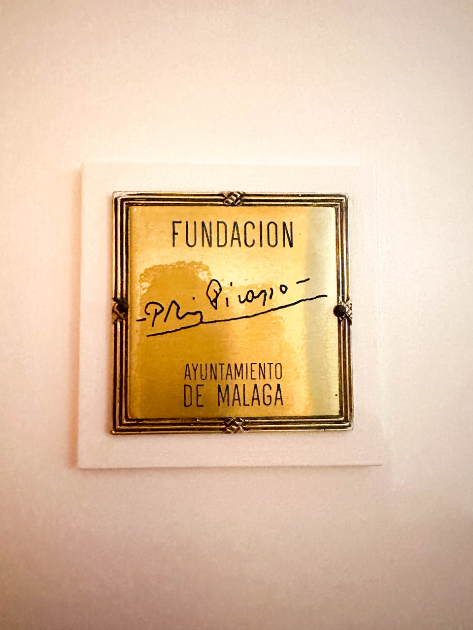 A close-up of a golden plaque inscribed with 'Fundación Picasso' and 'Ayuntamiento de Malaga', signed by Picasso