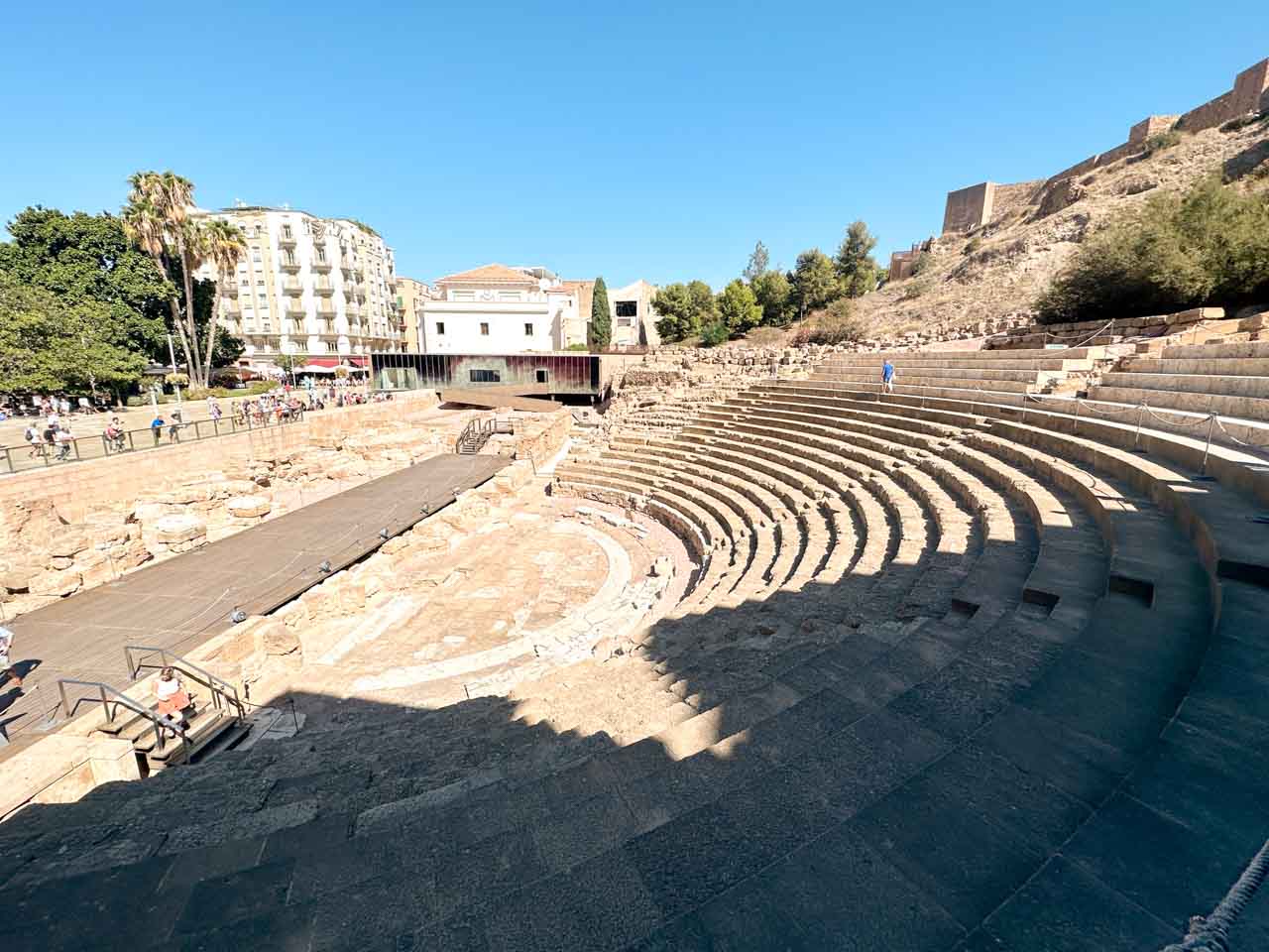 Roman Theatre (Teatro Romano) in Malaga, Spain - an ancient stone amphitheatre with rows of seating under a blue sky
