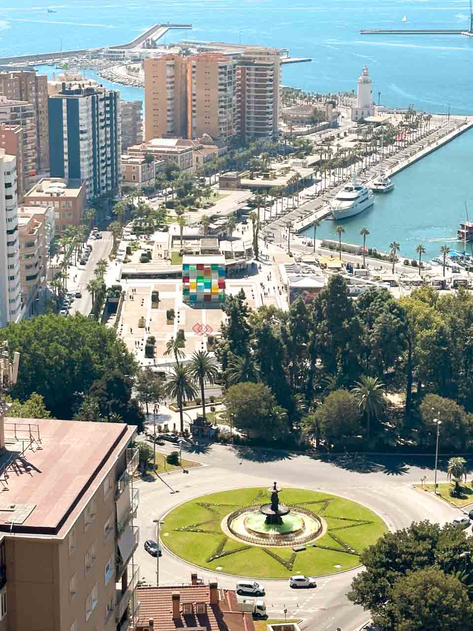 A bird's-eye view of a roundabout with a fountain in Malaga, the city&rsquo;s port, and Centre Pompidou