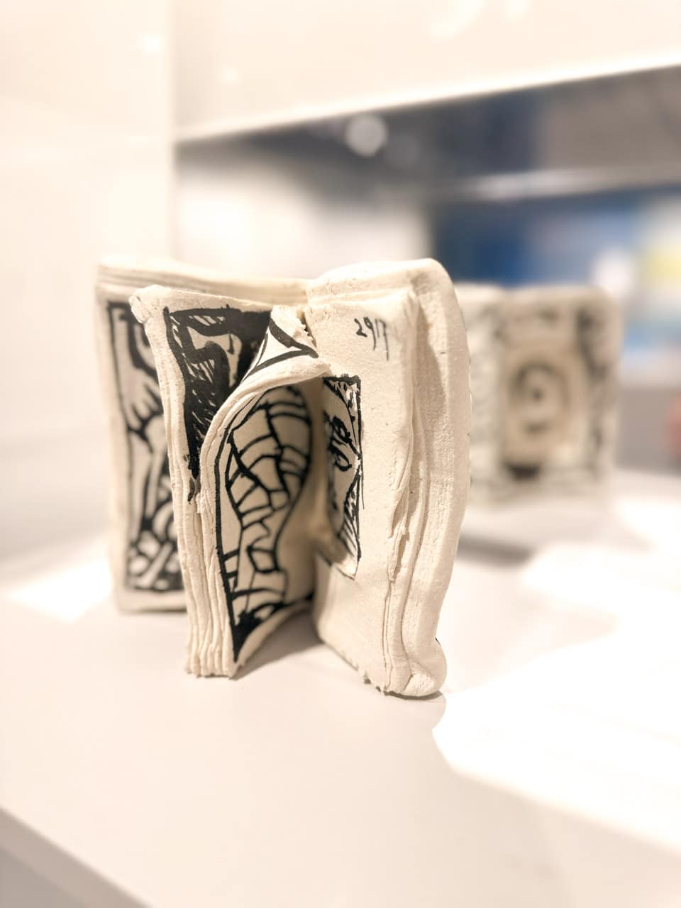 A close-up of a creatively sculpted ceramic book with black and white patterns on display at Centre Pompidou Malaga
