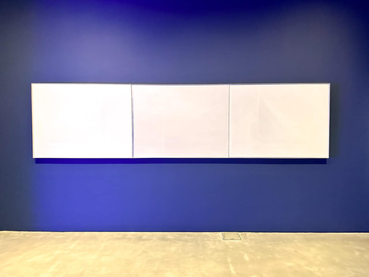 Three blank canvases mounted on a deep blue wall at Centre Pompidou Malaga
