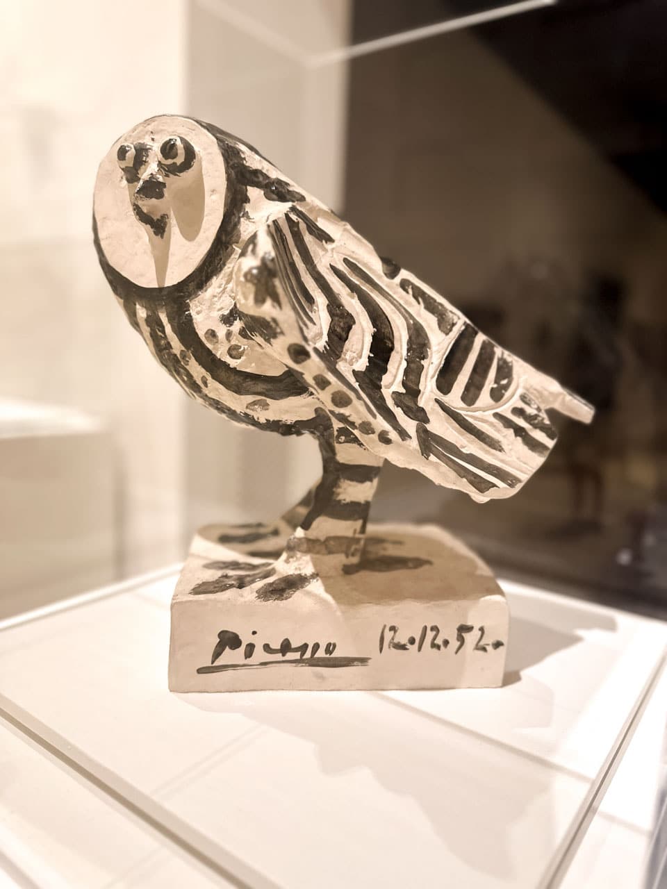 A painted owl sculpture by Pablo Picasso with black and white patterns, standing on a base with a signature and date