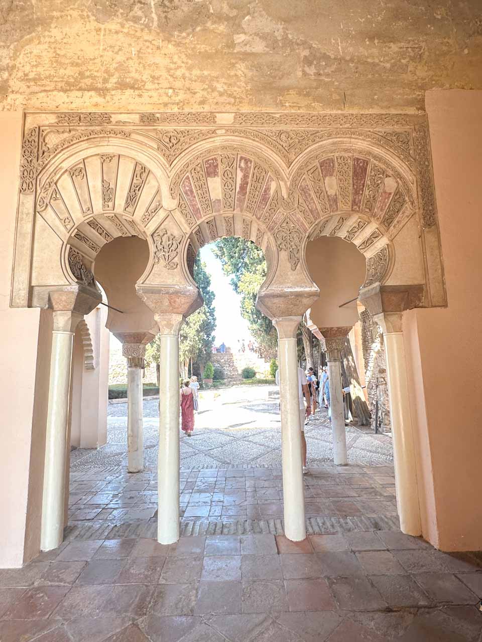 An arched gateway with elaborate Moorish designs and columns at the Alcazaba of Malaga