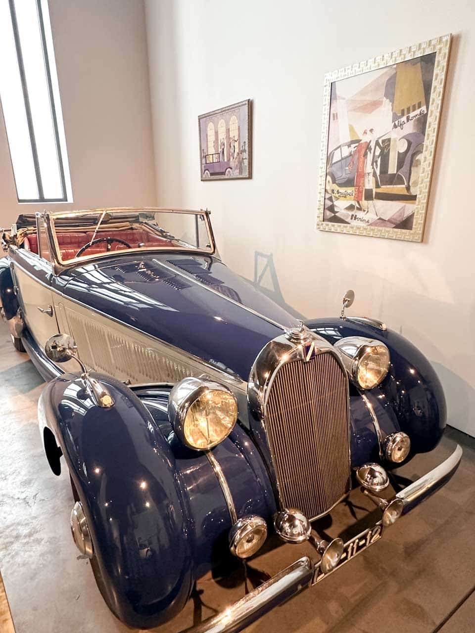 A vintage convertible car in deep blue with shiny chrome details and leather seats, exhibited at the Automobile and Fashion Museum in Malaga, Spain